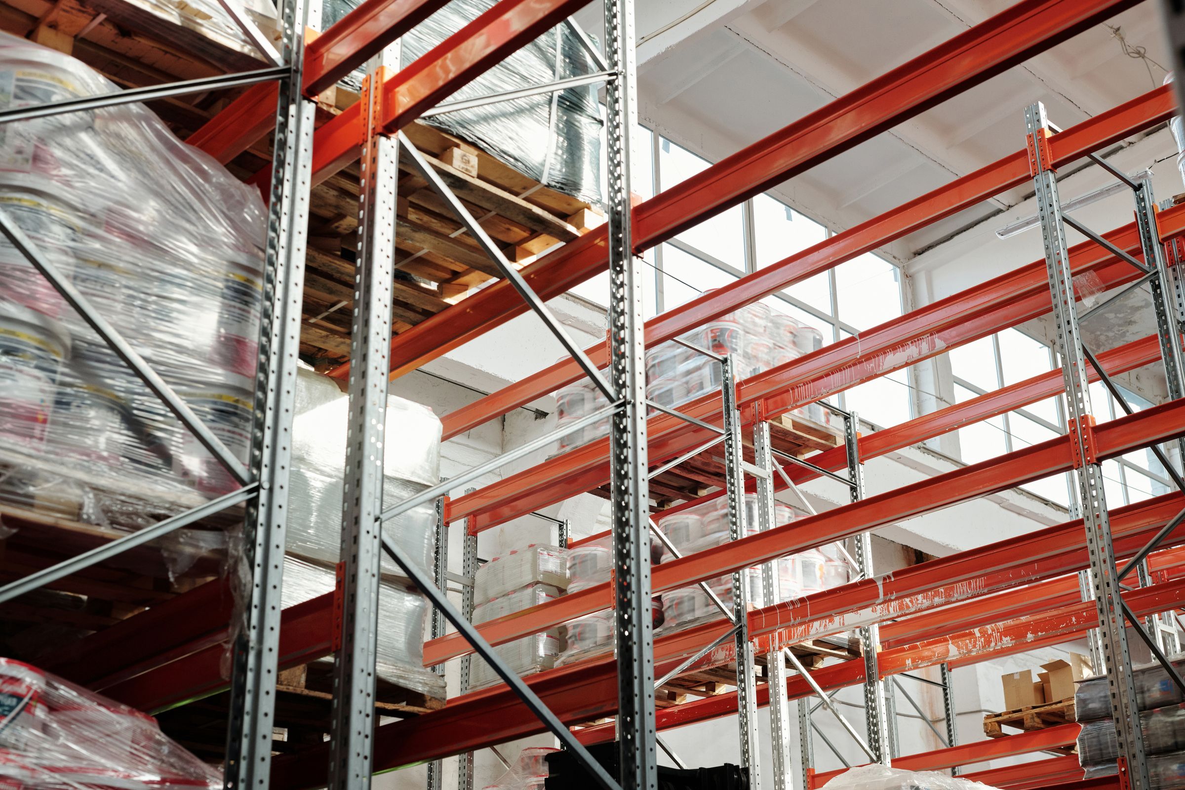 Aisle of a commercial warehouse with palletized inventory on tall steel racking