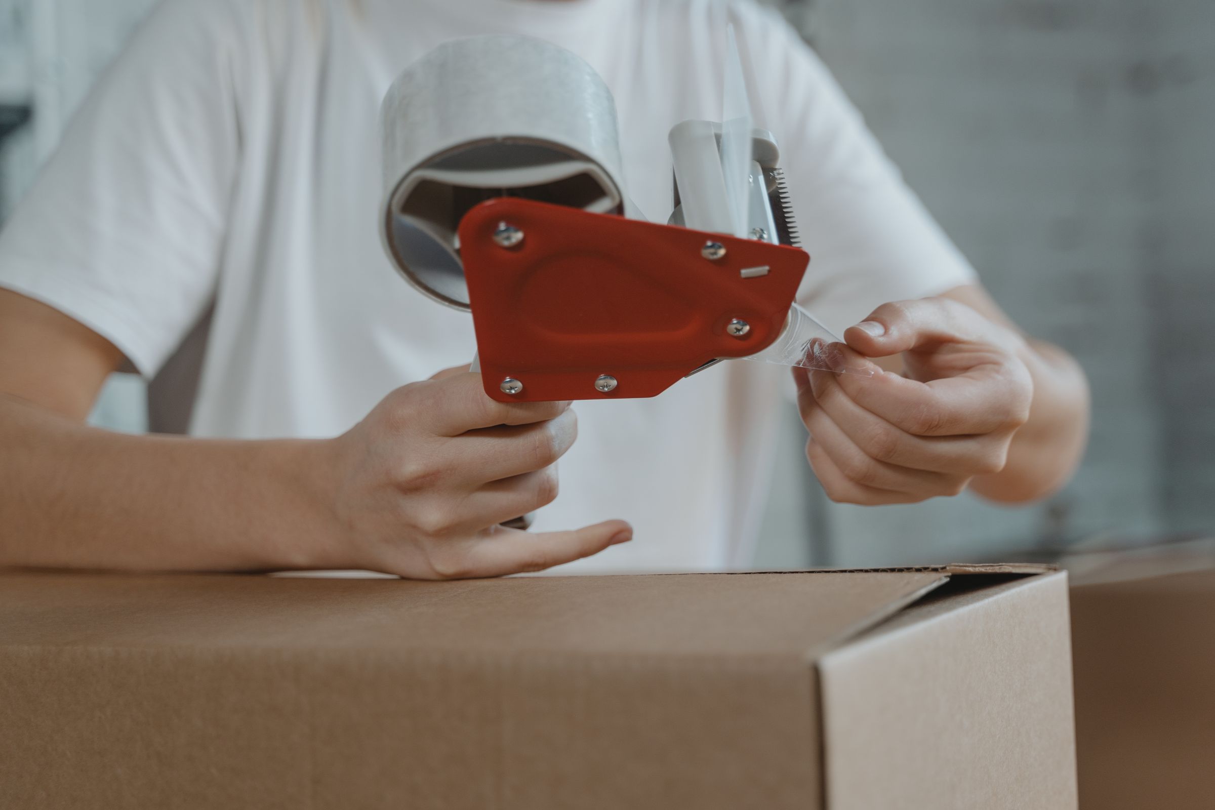 Worker sealing a shipping carton at a packing station